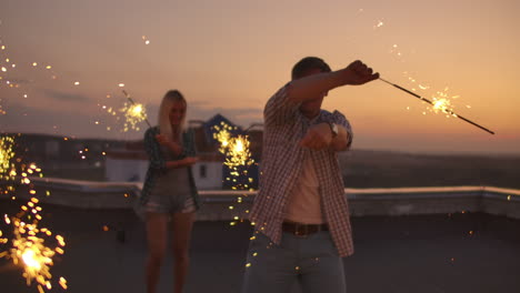 Young-Russian-boy-in-plaid-shirts-on-the-roof-moves-his-arms-and-body-a-dance-with-his-friends-on-a-summer-evening-with-big-bengal-light.